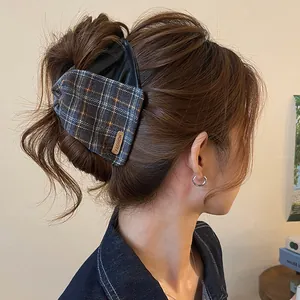 Close-up of a retro plaid and leather hair claw clip securing a chic bun hairstyle