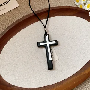 Close-up of vintage double cross pendant necklace with black leather cord detail