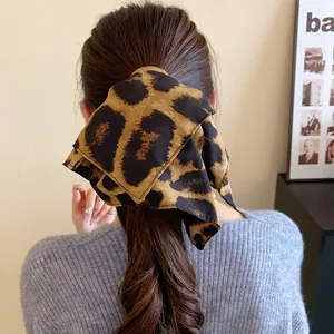 Dettaglio ravvicinato di uno scrunchie vintage leopardato acconciato in una coda di cavallo alta