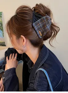 Close-up of a vintage plaid and leather shark clip on a woman's hair bun.