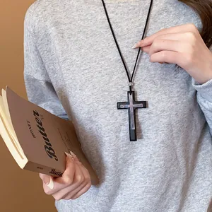 Detailed close-up of a retro leather double cross pendant necklace on a grey sweater