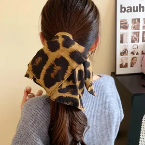 Dettaglio di un elastico per capelli plissettato leopardato in stile Maillard