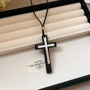 Close-up of vintage leather double cross necklace on a white jewelry display tray