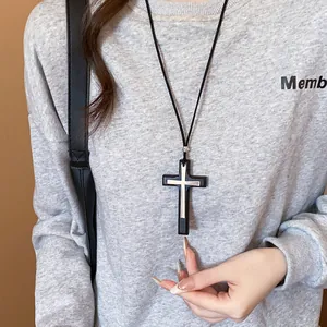 Detailed macro view of a vintage double layer cross pendant necklace on a grey sweatshirt