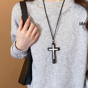 Close-up view of the leather and silver metal double cross pendant on a grey sweatshirt