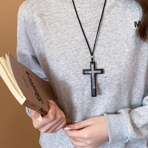 Close-up of a leather double cross pendant necklace worn on a grey sweater