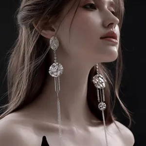 Close-up of elegant silver leaf tassel earrings featuring textured discs on a model