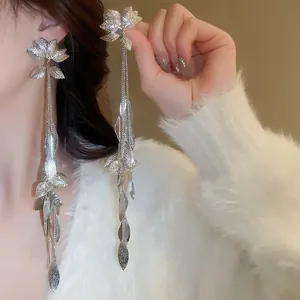 Detailed view of elegant long silver tassel earrings featuring delicate leaf charms