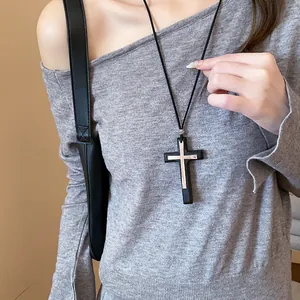 Detailed close-up showing a retro double cross pendant necklace on a grey knitted sweater