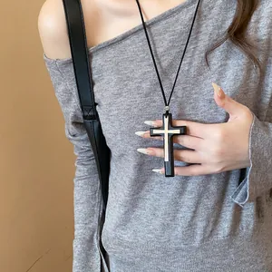 Detailed view of a vintage double cross pendant necklace worn with a grey sweater