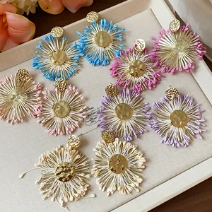 Close-up of colorful raffia flower stud earrings in various shades on a display tray