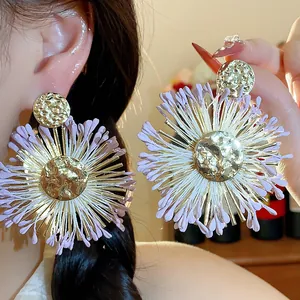 Detail shot of raffia flower earrings with hammered gold centers and purple petals.
