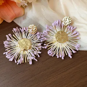 Detailed view of handmade raffia flower stud earrings with hammered gold centers