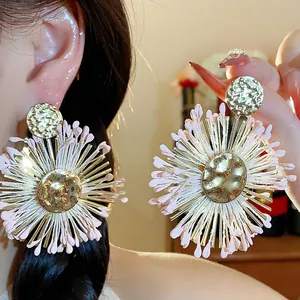 Detailed view of handmade raffia flower earrings with golden hammered metal center