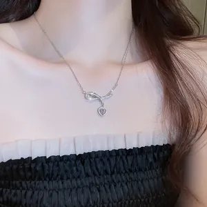 Dettaglio di una collana a fiocco d'argento con un ciondolo a cuore rosa scintillante