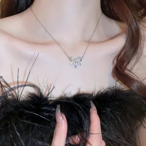 Primo piano di una collana a fiocco con diamanti e ciondolo a goccia rosa indossata su modella