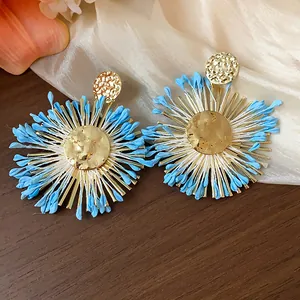 Macro view of the blue raffia petals and hammered golden core of these earrings.