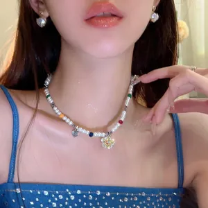 Primo piano di collana di perle con ciondolo a fiore indossata da modella