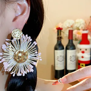 Close-up of pink raffia floral stud earring worn on model for vacation style.