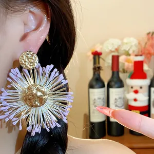 Close-up of light purple raffia flower earrings with gold hammered center