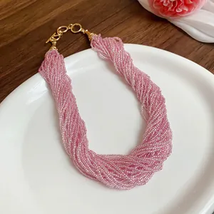 Dettaglio di un elegante collana multifilo di perle di vetro rosa con chiusura dorata