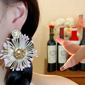 Detailed view of handmade pink raffia flower earrings with golden center on Asian model