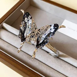 Detail view of an ornate butterfly open bangle with textured wings in a wood tray