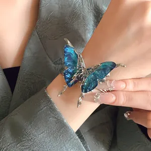 Close-up view of an oversized vintage butterfly cuff bracelet featuring blue gradient wings