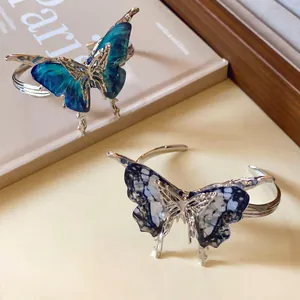 Detailed close-up of butterfly open cuff bracelets with blue and patterned wings