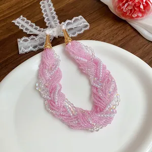 Primo piano di una dolce collana di perline rosa multifilo con fiocco in pizzo bianco.