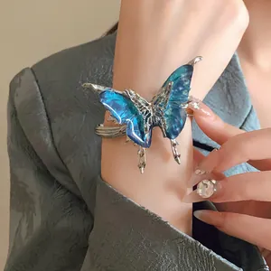 Detailed view of a stunning exaggerated blue butterfly open cuff bracelet on the wrist.