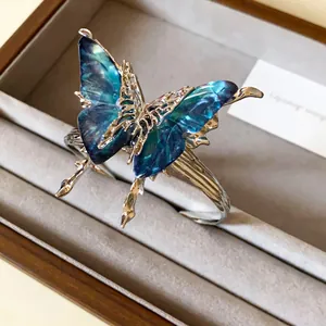 Macro view of blue translucent butterfly wings on a silver-toned pleated open bangle