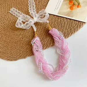 Dettaglio della collana di perle rosa a più strati con un delicato fiocco in pizzo bianco