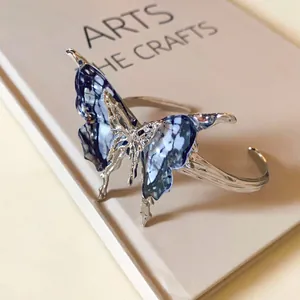 Macro shot of a butterfly open bangle featuring blue marbled wings on a silver frame.