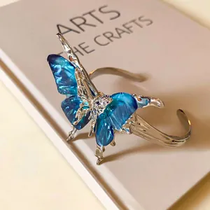Close-up of a blue butterfly open cuff bracelet with vintage textured silver-toned finish.
