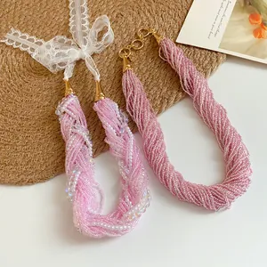 Dettaglio di collane di perle rosa multifilo con fiocco in pizzo bianco elegante