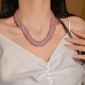 Primo piano di un elegante collana multistrato in perle di vetro rosa indossata da una modella.