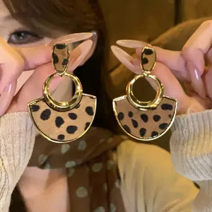 Gros plan de boucles d'oreilles rétro en forme d'éventail avec imprimé léopard et métal doré.