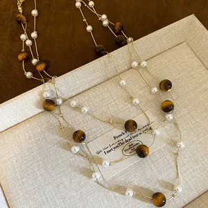 Elegant multi-layer gold plated sweater necklace featuring tiger eye stones and white pearls
