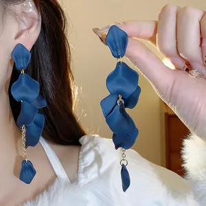 Primo piano di orecchini a nappa con petali blu scuro opaco e dettagli a catena oro