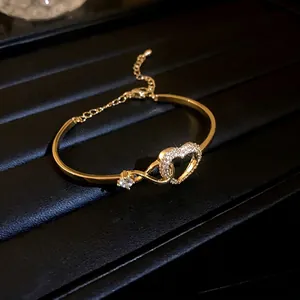 Elegant gold-tone bangle with sparkling heart-shaped zircon centerpiece and adjustable chain