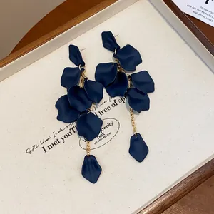 Elegante vista macro di orecchini a petalo blu navy con sottili nappe a catena dorata