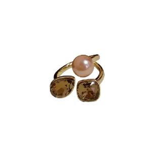 Elegant gold plated open ring featuring a lustrous pink pearl and brown crystal accents.