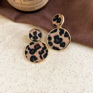 Détail macro de boucles d'oreilles rondes léopard vintage avec bords en métal doré