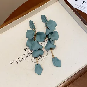 Primo piano di orecchini a nappa con petali blu opaco e catene dorate.