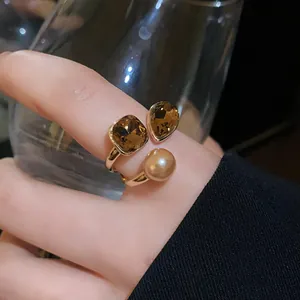 Detailed view of a gold-plated open ring featuring brown crystals and a champagne pearl.