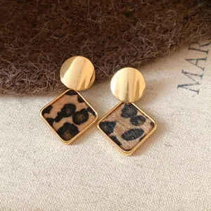 Vue détaillée de boucles d'oreilles dorées avec motif léopard en peluche
