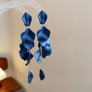 Dettaglio di orecchini con nappe a petalo blu scuro e catenine dorate vintage