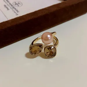 Close-up detail of a gold-plated adjustable ring with a pearl and champagne crystals.