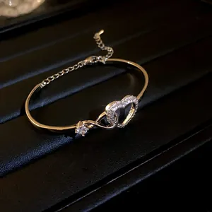 Close-up of elegant gold-toned heart bracelet with sparkling zircon embellishments